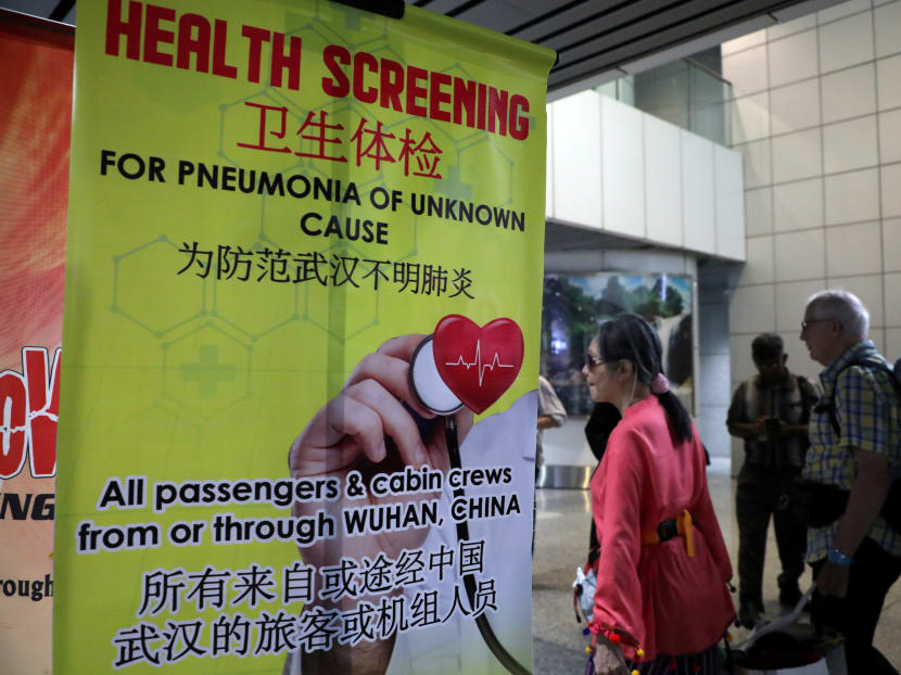 Passengers pass a banner about Wuhan Pneumonia at a thermal screening point in the international arrival terminal of Kuala Lumpur International Airport in Sepang, Malaysia, Jan 21, 2020.