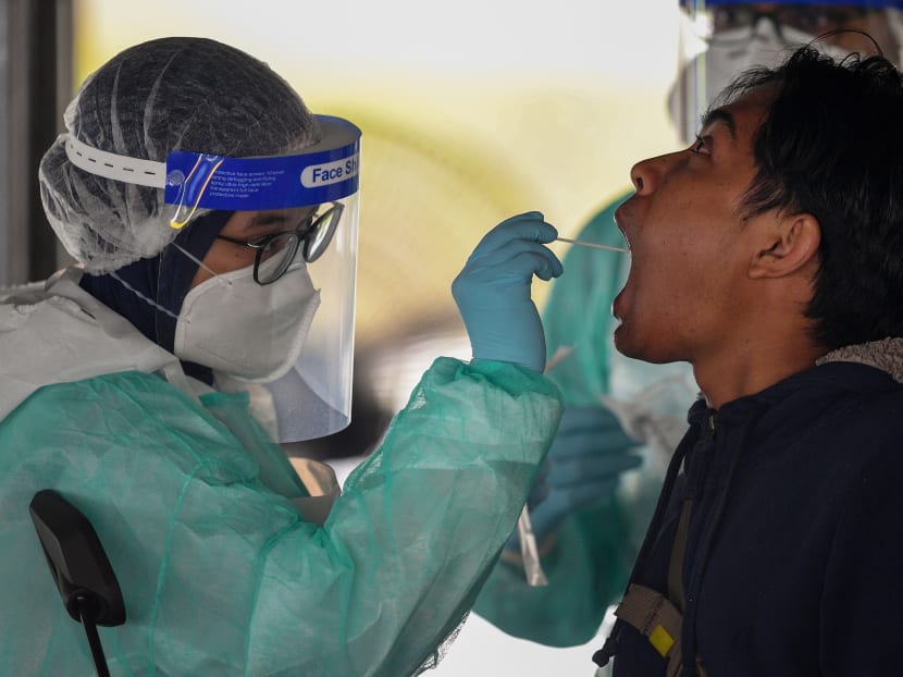 A health worker uses a swab to collect a sample for Covid-19 coronavirus testing from a man in Gombak on the outskirts of Kuala Lumpur on April 22, 2020.