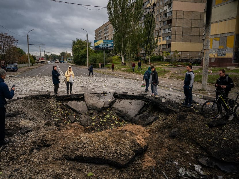Local residents examine a crater following a missile strike in Dnipro on Oct 10, 2022, amid Russia's invasion of Ukraine.