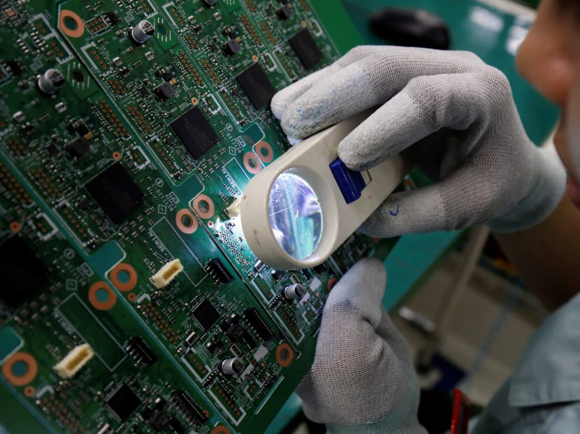 A woman looks through a magnifying glass to check errors on a printer circuit board at Manutronics Factory in Bac Ninh province, Vietnam, May 30, 2018.