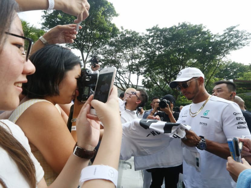 Mercedes driver Lewis Hamilton signing autographs at a private session at the Ritz Carlton yesterday. The Briton leads the championship but feels the twisty Singapore circuit may favour Red Bull and Ferrari. Photo: Koh Mui Fong