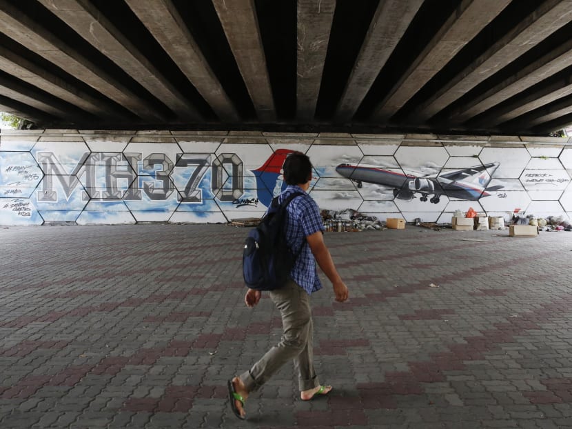 A man walks past graffiti depicting the missing Malaysia Airlines flight MH370. Reuters file photo