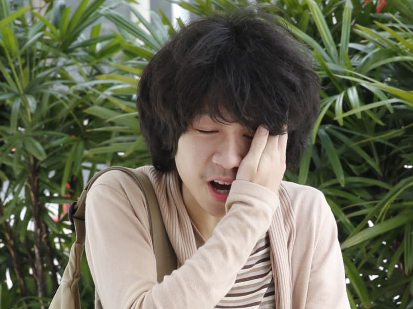 Amos Yee grimacing after being struck on the face by an unidentified man before attending his court hearing. Photo: Ernest Chua/TODAY