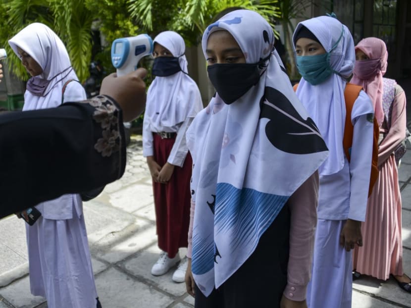 This file photo taken on June 10, 2020 shows students queueing up to get their temperature taken at a junior high school in Banda Aceh.
