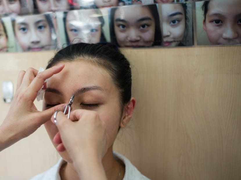 Daisy Tse has her eyebrows plucked by trained face reader Li Chau-jing, who makes slight changes to her client's brows to bring them better luck, at Li's shop in Hong Kong. Photo: AFP