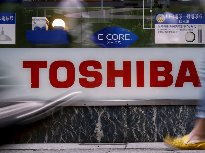 Pedestrians walk past a logo of Toshiba Corp outside an electronics retailer in Tokyo, Japan, June 25, 2015. Photo: Reuters