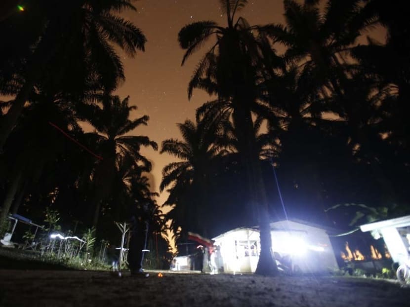 An immigrant enforcement officer stands outside makeshift shelters of migrant workers, as light trails of torches used by the officers during their search for hiding illegal workers are seen, during a crackdown on illegal migrant workers in a palm plantation in Nilai, outside Kuala Lumpur on Sept 1, 2013. An immigrant enforcement officer stands outside makeshift shelters of migrant workers, as light trails of torches used by the officers during their search for hiding illegal workers are seen, during a crackdown on illegal migrant workers in a palm plantation in Nilai, outside Kuala Lumpur on Sept 1, 2013.