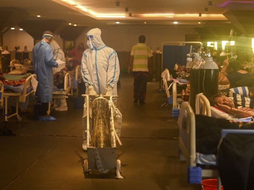 Health workers wearing personal protective equipment attend to Covid-19 coronavirus positive patients inside a banquet hall temporarily converted into a Covid-19 care centre in New Delhi on April 28, 2021.
