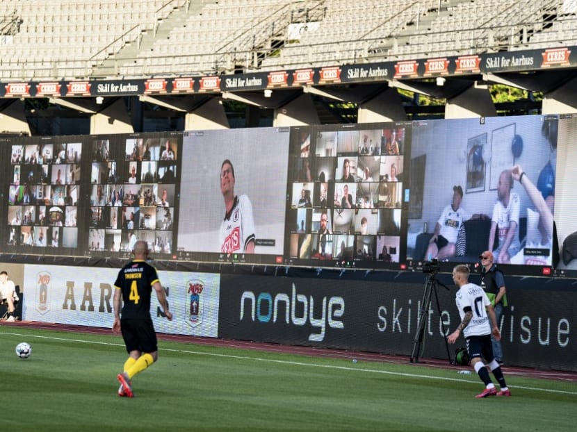 Players vie for the ball as fans are streamed live onto screens on the stands during the Danish Super League football match between AGF and Randers FC on  May 28, 2020.