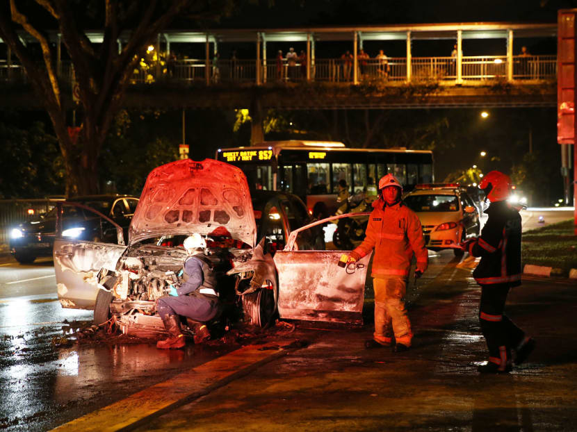 SCDF personnel inspecting the charred remains of a car which caught fire along Ang Mo Kio avenue 6. Photo: Don Wong