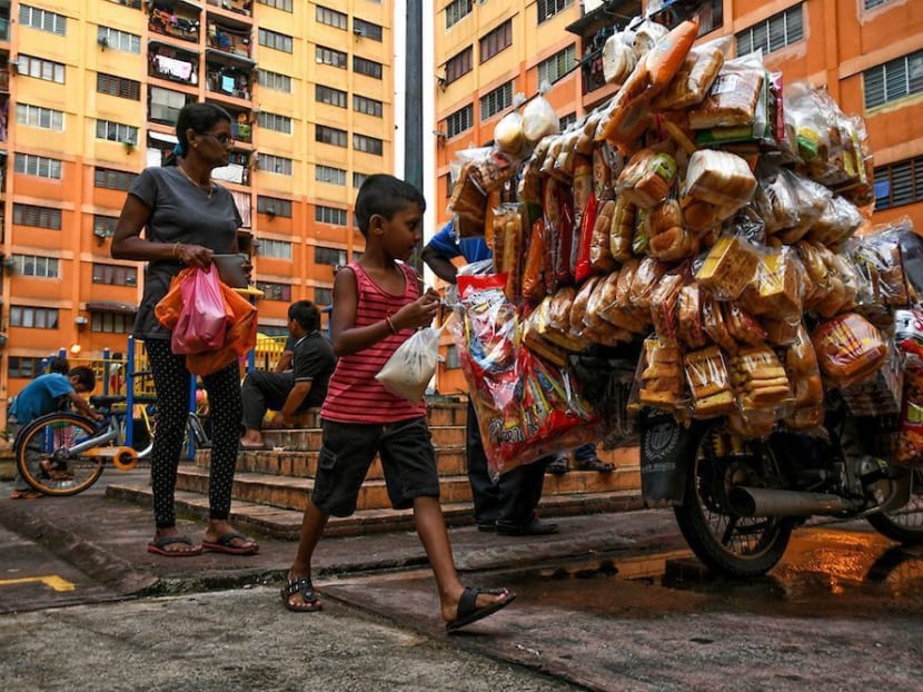 Residents from government low-cost flats with packets of food walk past the breadman. A Unicef study finds that Malaysian children in urban poor environments were “heavier”, or suffering from obesity due to a diet that contained larger amounts of refined sugars found in cheap processed foods. Photo: The Malaysian Insight