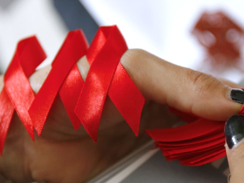 An Aids awareness volunteer prepares red ribbons to be distributed to commuters. Photo: AFP