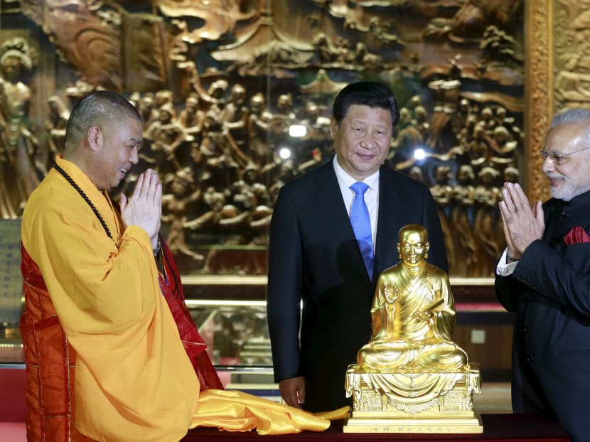 Chinese President Xi Jinping, center, looks on as Indian Prime Minister Narendra Modi (R) receives a golden Buddha statue from a Buddhist abbot of Dacien Buddhist Temple in Xian, Shaanxi province, China, May 14, 2015. Photo: REUTERS