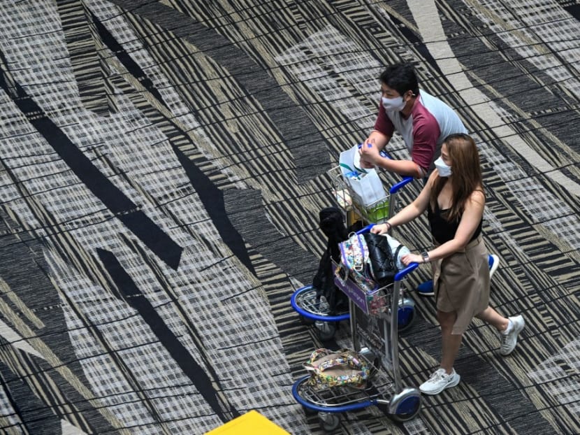 Travellers walk along the transit hall of Changi International Airport in Singapore on March 11, 2022. Travellers walk along the transit hall of Changi International Airport in Singapore on March 11, 2022.
