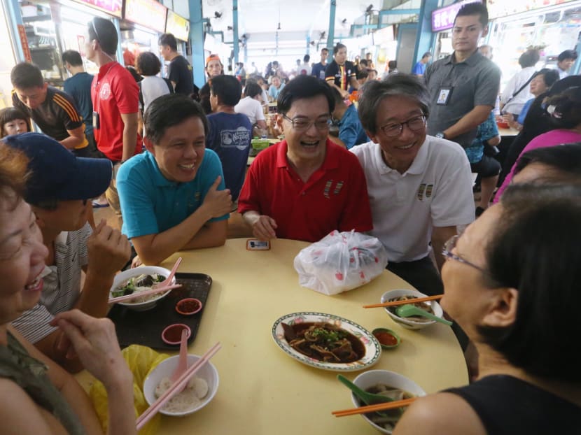 L to R: Trade and Industry Minister Chan Chun Sing (in blue), Deputy Prime Minister Heng Swee Keat and former Cabinet Minister Lim Swee Say speaking to residents during their walkabout at a Bedok South market on Saturday (July 27).