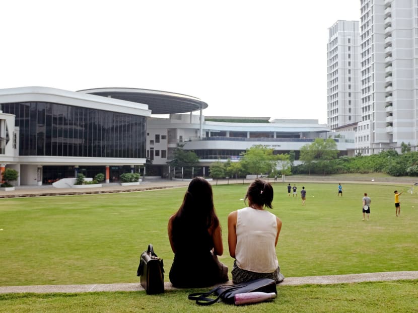 Young voter Diyana (left), 22, who works in the finance industry, and a friend sit at the Town Green at the National University of Singapore’s University Town as students engage in a game of Ultimate Frisbee. Many first-time voters said they were experiencing mixed feelings of excitement and apprehension as the national significance of their vote dawns on them.  Photo: Tang Chee Seng