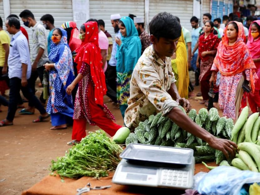 FILE PHOTO: A man sells vegetables on the street while garment workers come out of a factory during the lunch break, as factories reamain open during a countrywide lockdown, in Dhaka, Bangladesh, July 6, 2021. REUTERS/Mohammad Ponir Hossain