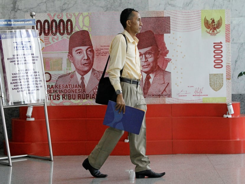 A man walks past a poster of an one hundred thousand rupiah bank note inside Indonesia's central bank, Bank Indonesia, in Jakarta, Indonesia July 21, 2016. REUTERS/Iqro Rinaldi