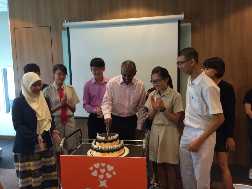 Minister K Shanmugam cutting the BMDP's 21st birthday cake, along with the 100th donor Mr Lim Yun Song and student representatives.