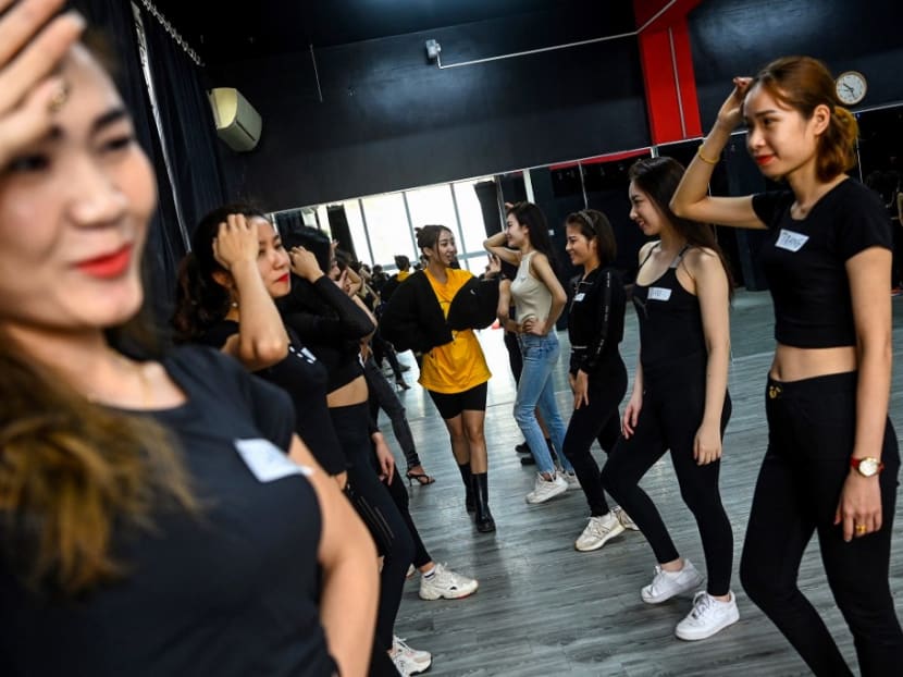 This photograph taken on March 2, 2021 shows instructor Pham Kieu Ly (centre) demonstrating a pose to participants during a course teaching them how to pose for photographs on their mobile phones at a studio in Hanoi.
