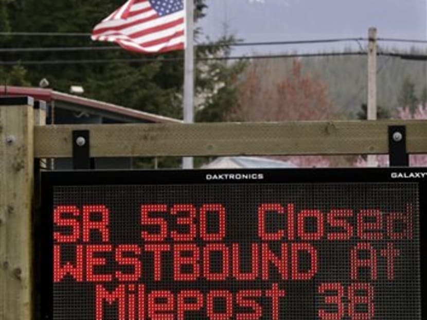A road sign advising the closure of Highway 530 stands in view of a flag still at half-staff on April 15, 2014, in Darrington, Washington. Photo: AP