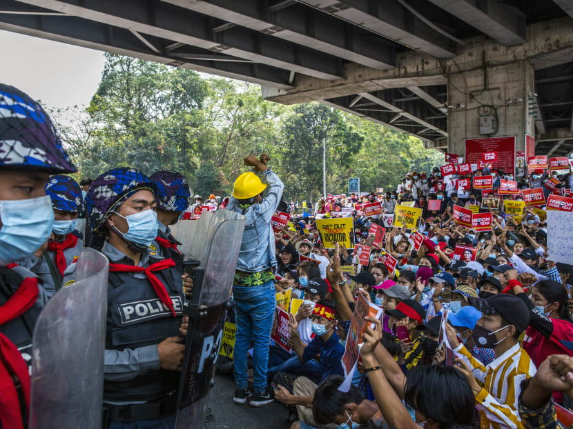 Police in riot gear look on as demonstrators protest against the military coup in Yangon, Myanmar. The military has sought to crack down on internet usage in part to keep protesters from organising.