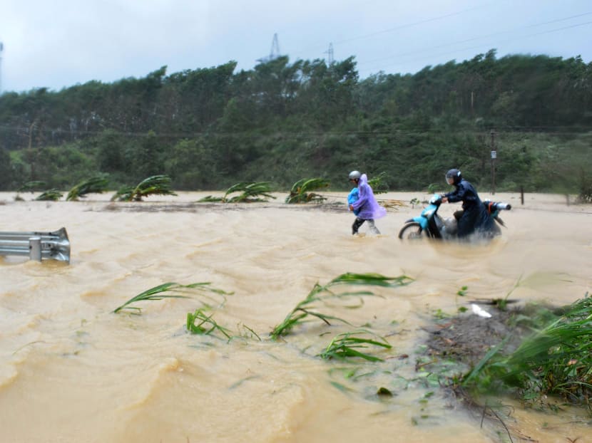 This picture taken on November 4, 2017 shows people walking through floodwaters on a highway in the central province of Dak Lak brought by Typhoon Damrey. Photo: AFP