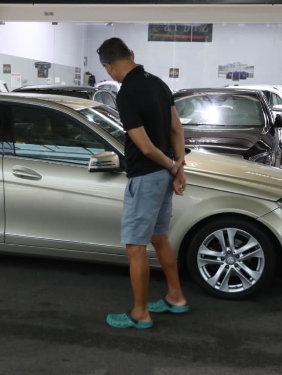 A man looking at a car that was being sold in a showroom in Singapore. A man looking at a car that was being sold in a showroom in Singapore.