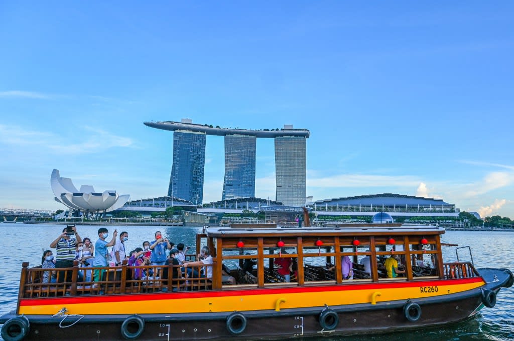 In this photograph taken on Feb 18, 2022, people take a boat tour before the Marina Bay Sands hotel and resort in Singapore. In this photograph taken on Feb 18, 2022, people take a boat tour before the Marina Bay Sands hotel and resort in Singapore.
