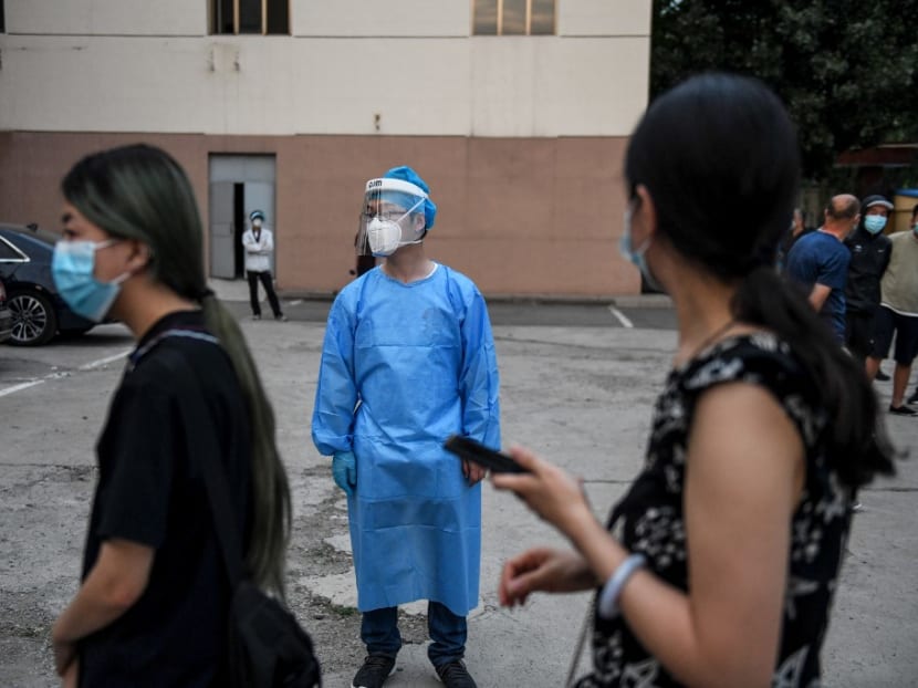 People who had their car number plates recorded in the area of the Xinfadi market where a new Covid-19 cluster emerged last week, wait to do swab tests for the coronavirus as a medical worker stands nearby at a testing centre in Beijing on June 17, 2020.