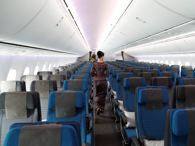 A stewardess with Singapore Airlines walks through the economy seating of the airline's Boeing 787-10 Dreamliner. Earlier on Monday, SIA had announced that it will cut 96 per cent of the flight capacity that had been originally scheduled up to end-April, as border controls tighten worldwide due to the Covid-19 outbreak.