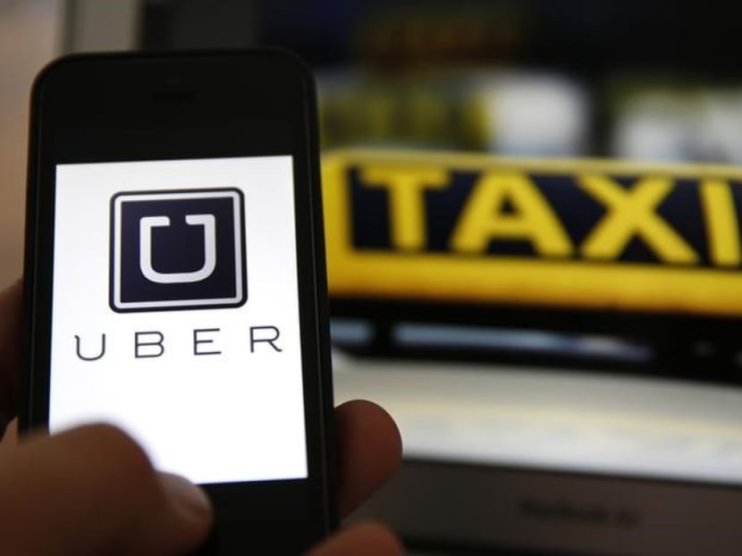 An illustration picture shows the logo of car-sharing service app Uber on a smartphone next to the picture of an official German taxi sign. Photo: Reuters