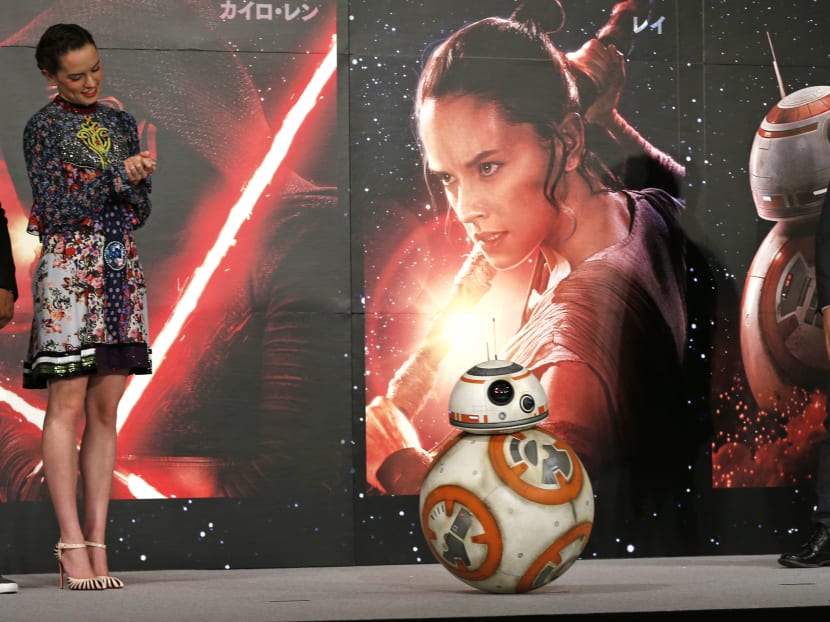 Director JJ Abrams, right, and actress Daisy Ridley look on BB-8 droid during a press conference for their latest film "Star Wars: The Force Awakens" at a hotel in Urayasu, near Tokyo. Photo: AP