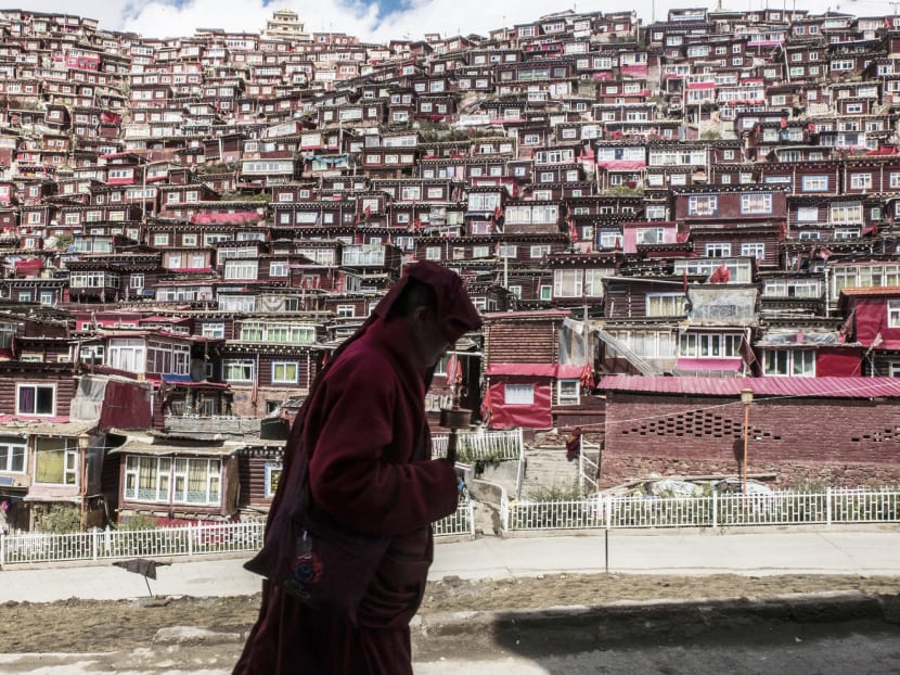 A Buddhist nun with a prayer wheel in Larung Gar, China, the world’s largest Buddhist institute, where demolition teams are cutting through an extraordinary vista of hand-built red dwellings. Photo: The New York Times