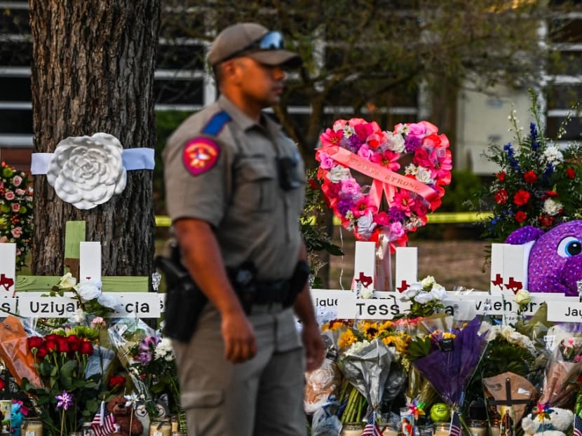 In this file photo taken on May 27, 2022, a police officer stands near a makeshift memorial for the shooting victims outside Robb Elementary School in Uvalde, Texas.&nbsp;