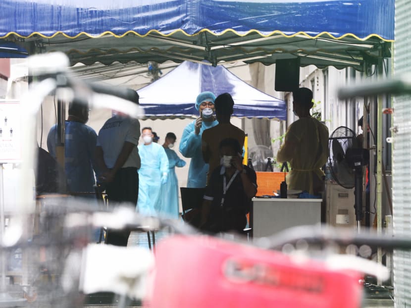 A foreign worker is seen with a healthcare personnel at Westlite Woodlands dormitory on April 22, 2021.