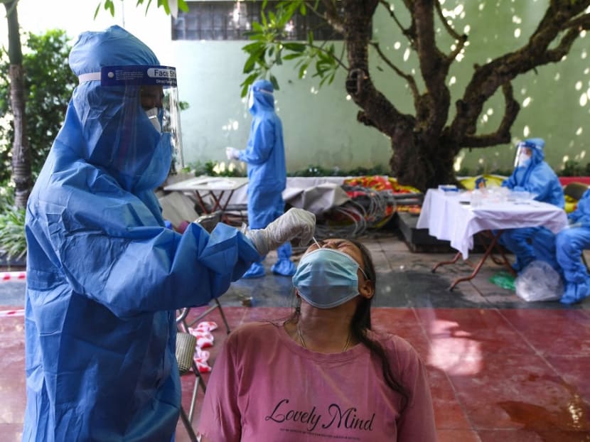 A health worker wearing personal protective equipment collects a swab sample from a woman for Covid-19 coronavirus testing in Hanoi on Aug 29, 2021.