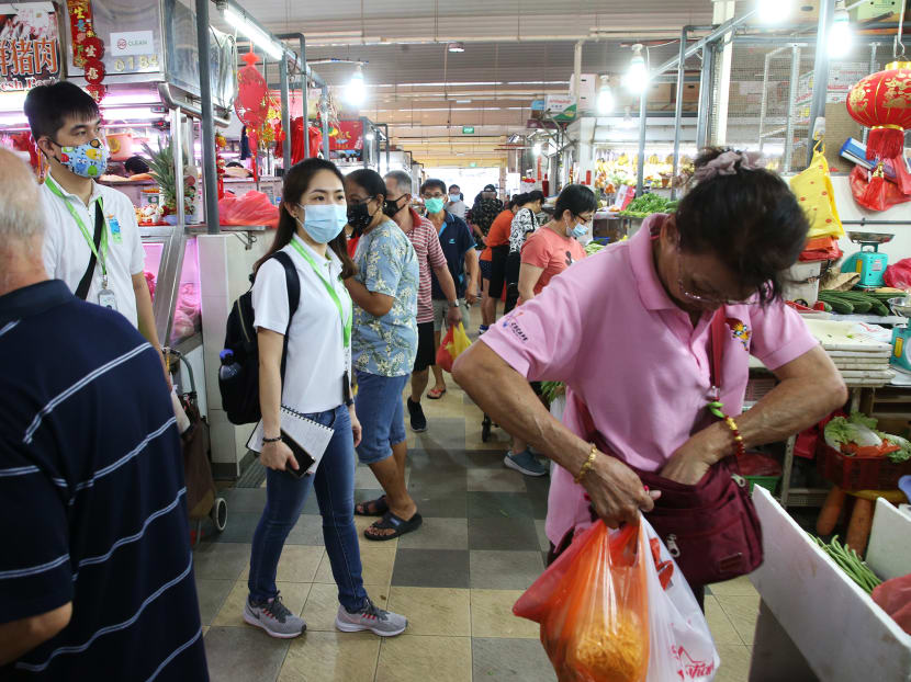 Two National Environment Agency officers patrolling Chong Boon Market to ensure safe distancing is practised during an enforcement operation on April 10, 2020.