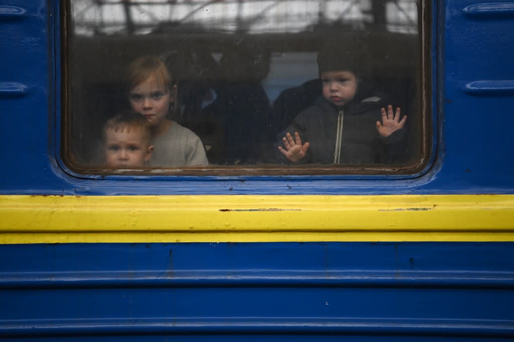 Children look out from a carriage window as a train prepares to depart from a station in Lviv, western Ukraine, enroute to the town of Uzhhorod near the border with Slovakia, on March 3, 2022. 