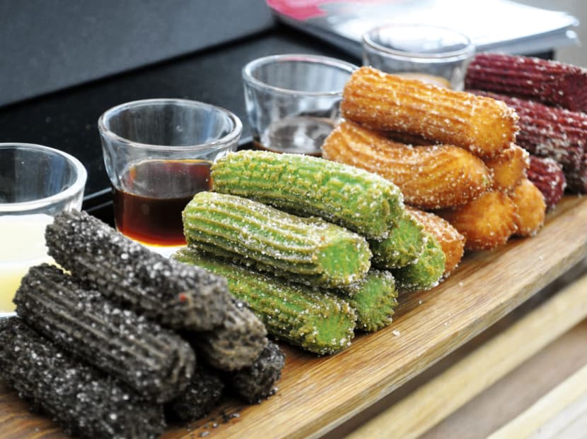 Churros Matcha yang renyah dengan taburan gula halus dan matcha bubuk, disajikan dengan saus celup cokelat yang lezat