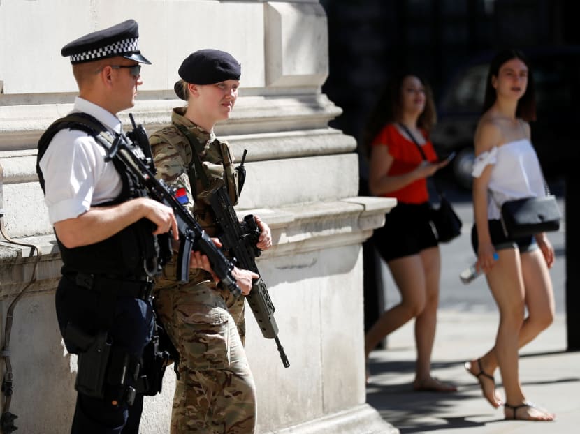 Tourists walk past a soldier and an armed police officer on duty in Whitehall, London. Photo: Reuters