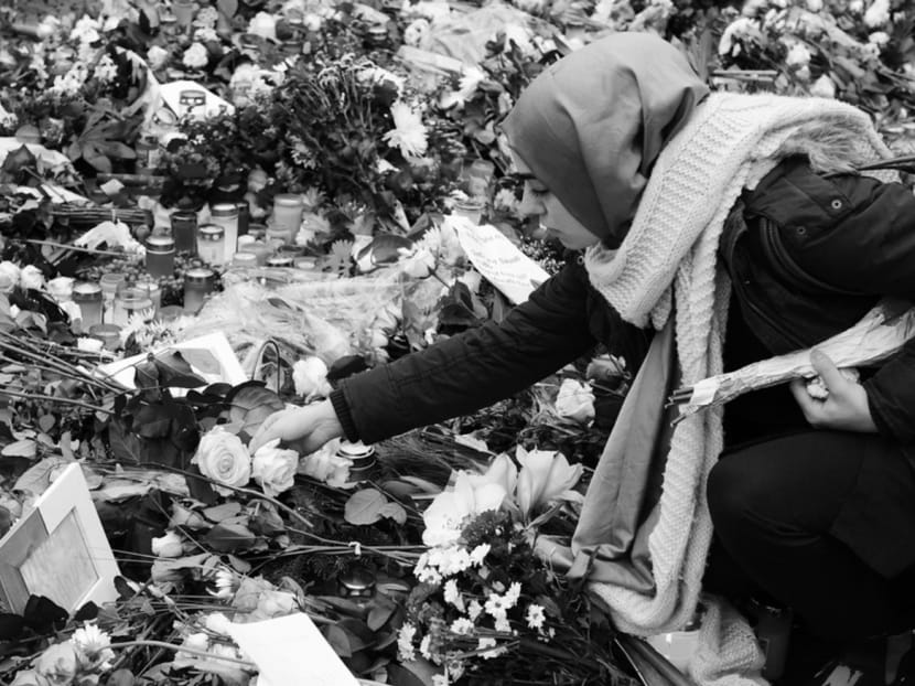 A Muslim woman laying flowers at a memorial for the victims of the France attacks, in Berlin. Photo: AFP