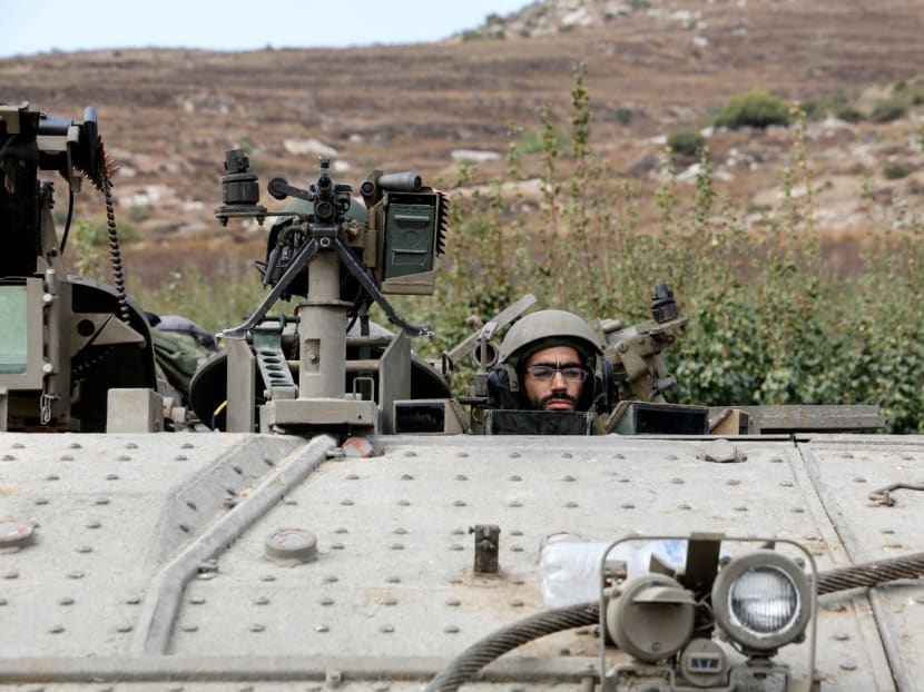 An Israeli soldier looks out from an armoured personnel carrier near Israel's border with Lebanon on Oct 9, 2023.