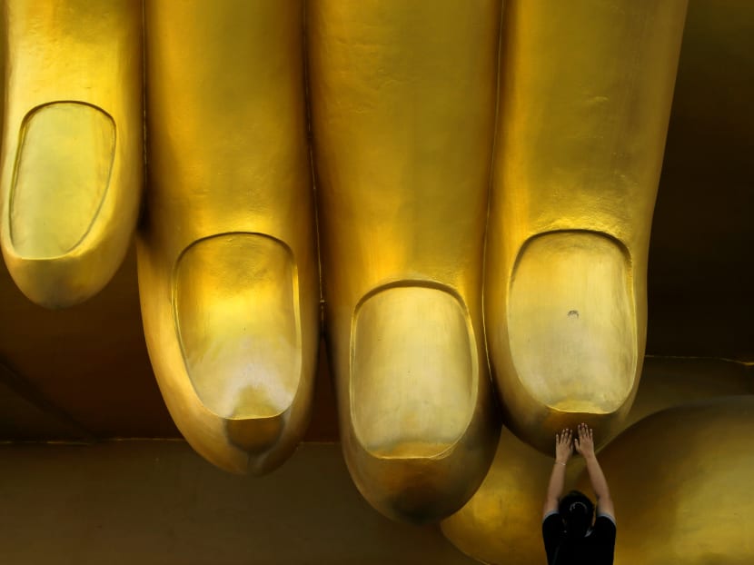 A woman prays while touching the fingers of a Buddha statue in Ang Thong, Thailand, on Makha Bucha Day, which falls on on February 11, 2017. Makha Bucha Day celebrates Buddha's teachings and is one of the most important dates in the Buddhist calendar. Photo: Reuters