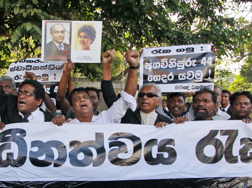 Sri Lankan rights activists and lawyers shout slogans against current chief justice Mohan Peiris during a protest outside the Supreme court, seen in a placard on the left, and also seen photograph of former chief justice Shirani Bandaranayake, who was sacked by then president Mahinda Rajapaksa, in Colombo, Sri Lanka, today (Jan 28). Photo: AP
