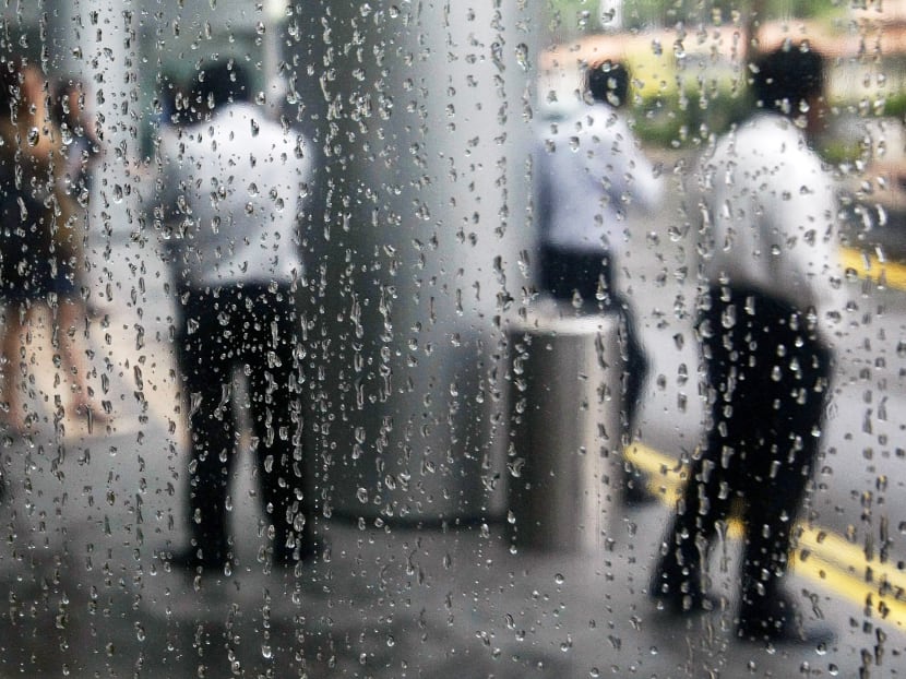 Office workers are reflected in a rain-covered window as they stand at the lobby of a building in Singapore's financial district. Reuters file photo