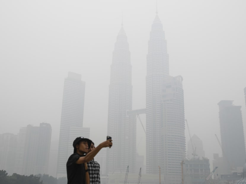 Tourists take a selfie against Malaysia's landmark building Petronas Twin Towers shrouded with haze in Kuala Lumpur, Malaysia on Saturday, Sept. 26, 2015. Photo: AP