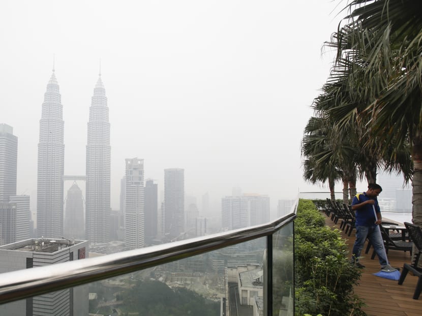 A maintenance worker sweeps against Malaysia's landmark building, Petronas Twin Towers shrouded with haze in Kuala Lumpur, Malaysia, Oct 20, 2015. Photo: AP