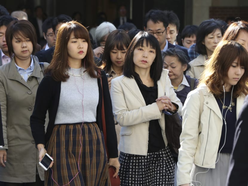 In this Monday, Oct. 26, 2015 photo, commuters cross a street during morning rush hour in Tokyo. AP file photo