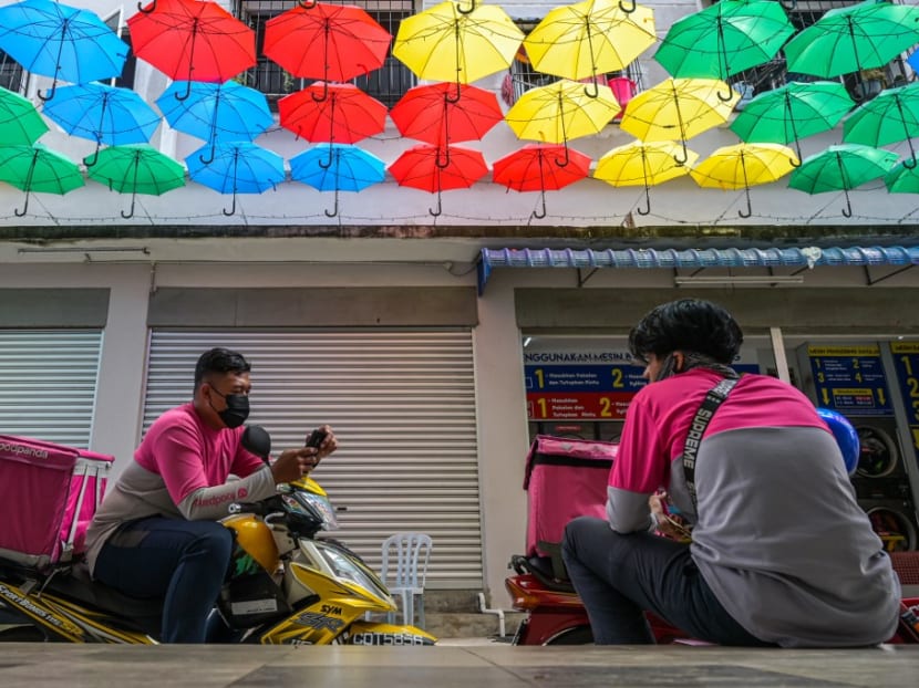 Two Foodpanda delivery motorcycle riders wait for orders in Mentakab in Malaysia's Pahang state on Jan 19, 2021.